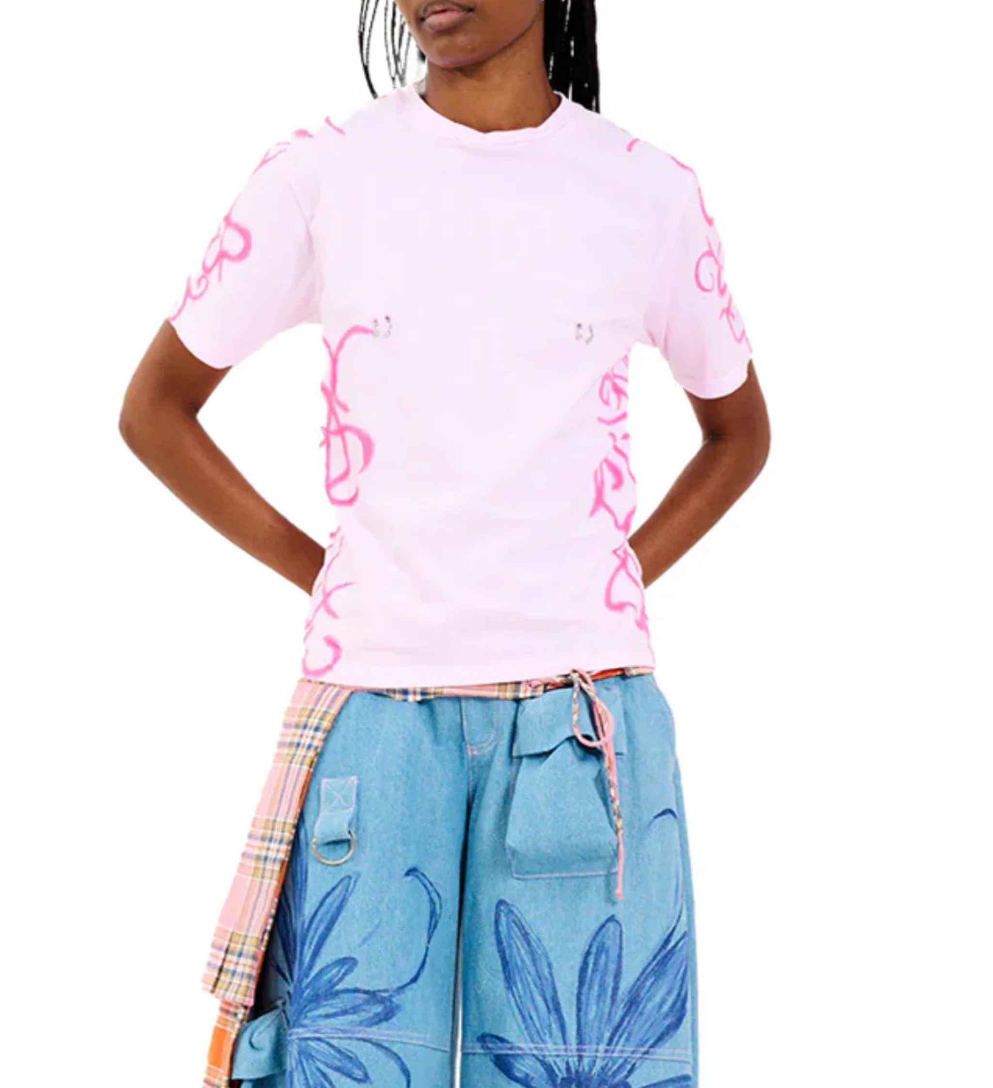 Model wearing pink short sleeve t-shirt with pink graffiti details and blue floral wide-leg pants with plaid sash