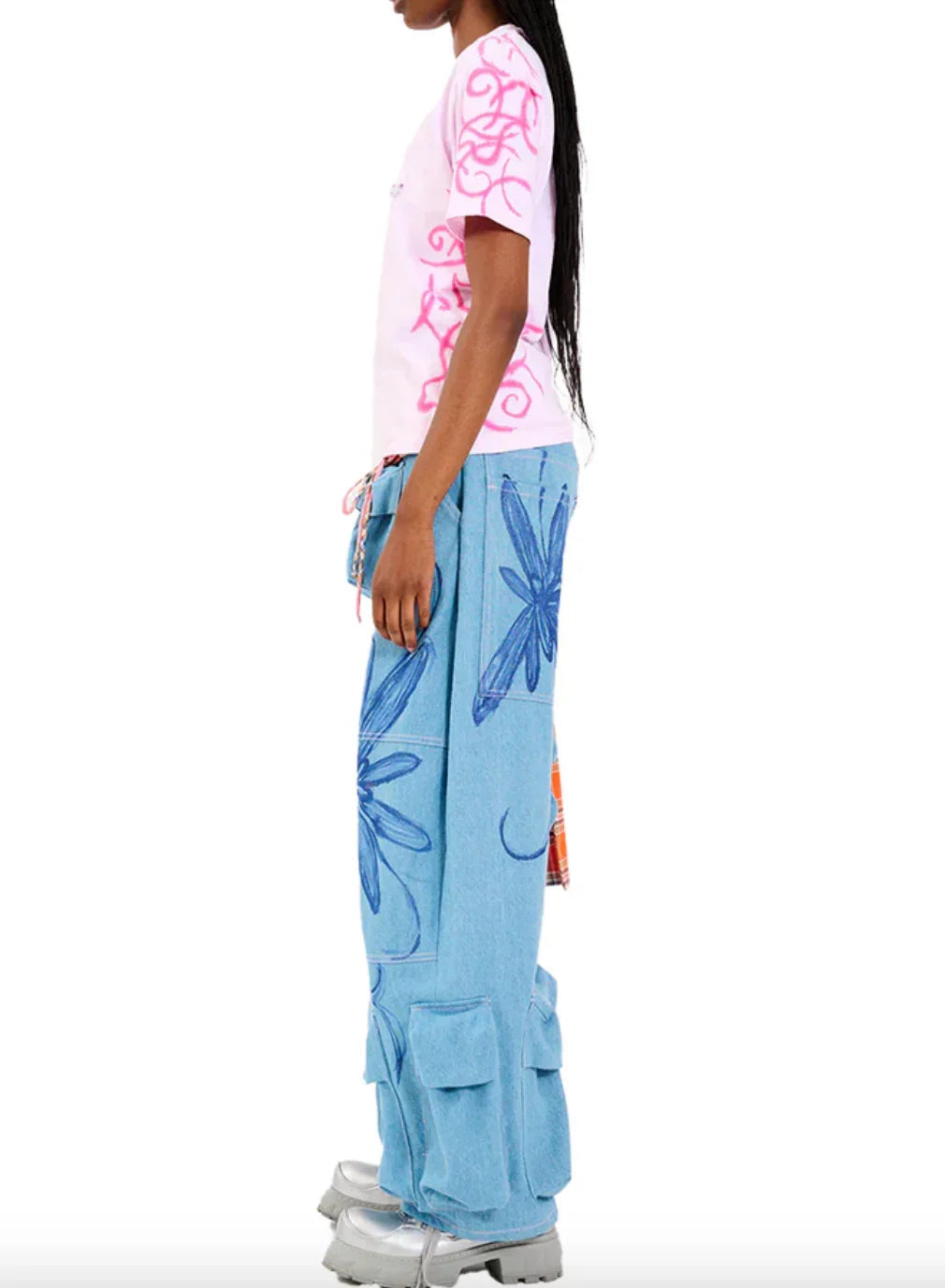 Side view of woman wearing pink graphic t-shirt and blue cargo pants with blue floral prints