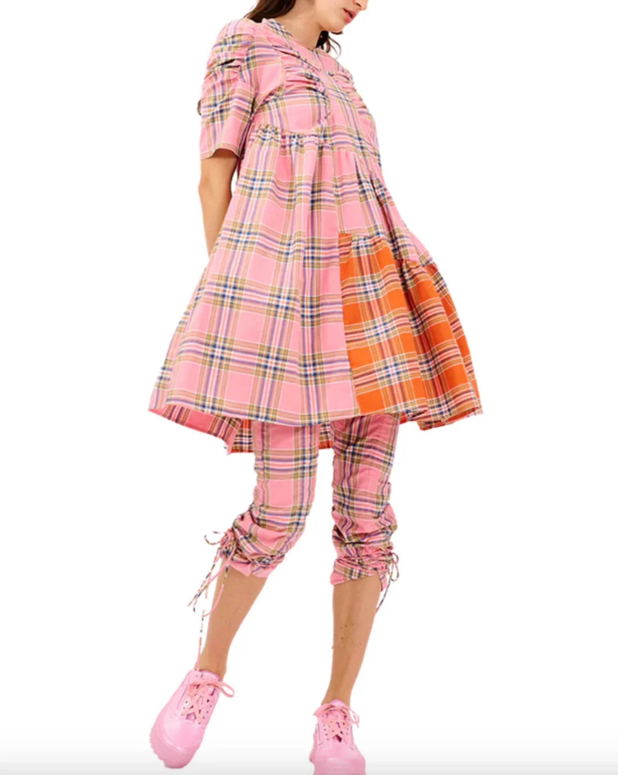 Woman in pink and orange plaid oversized dress with matching scrunched pants and pink shoes