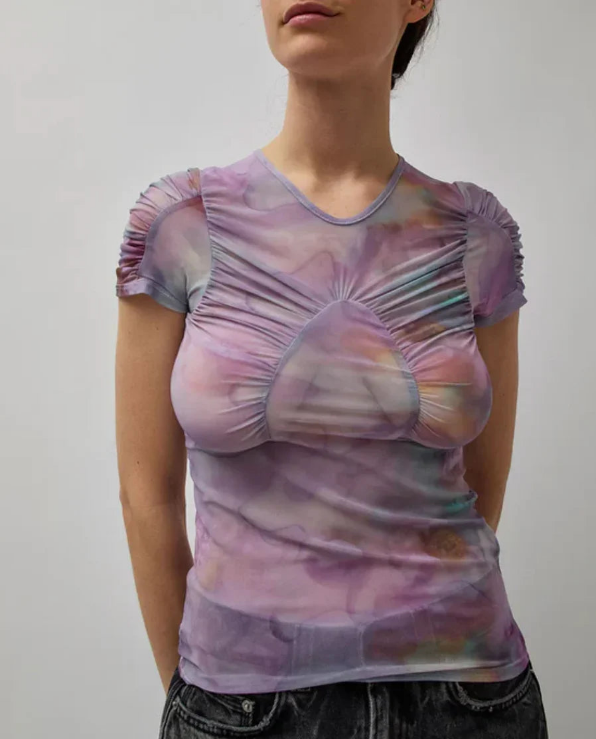 Woman wearing a ruched mesh top with purple tie-dye pattern and puffed short sleeves