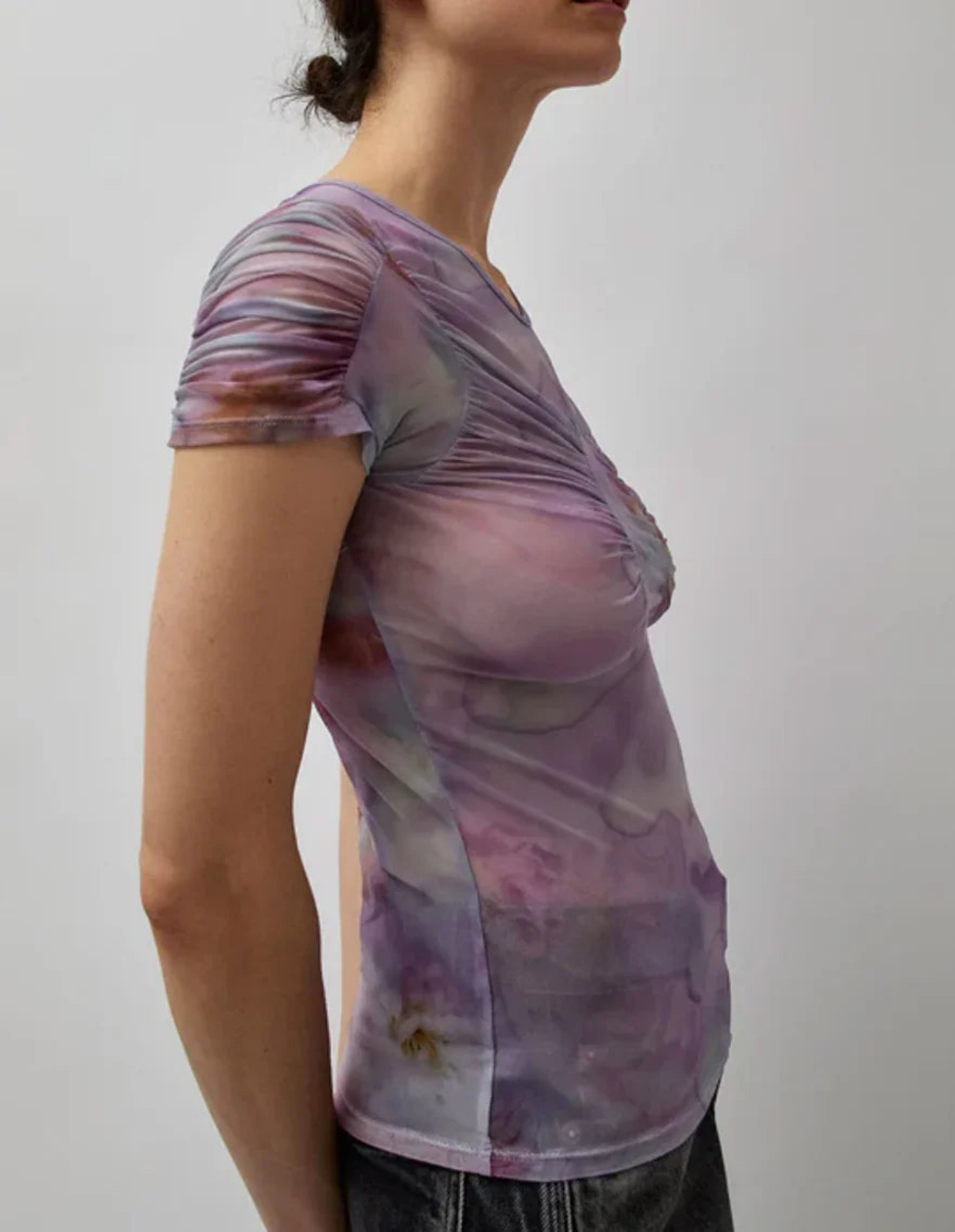 Side view of woman wearing a fitted purple tie-dye ruched short sleeve top