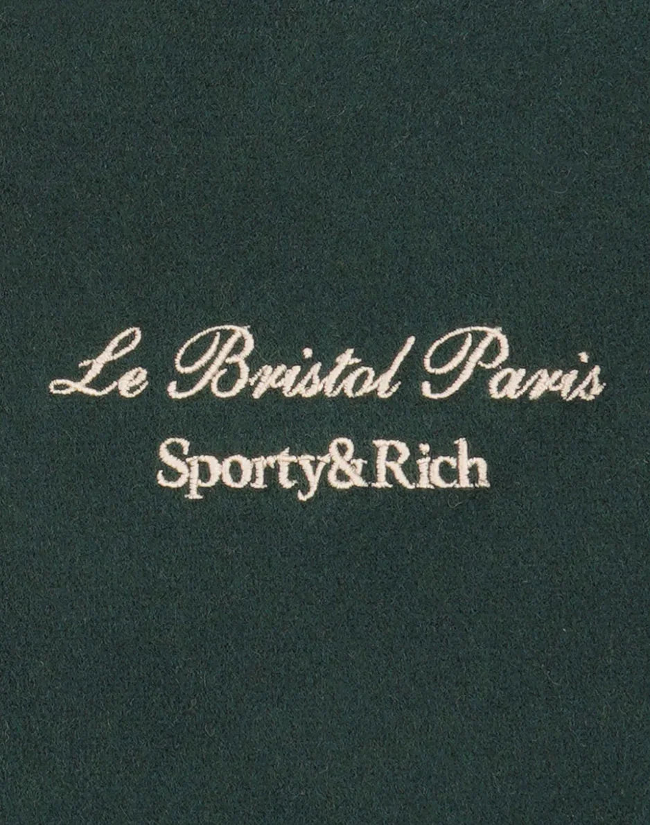Dark green fabric with white embroidered text Le Bristol Paris Sporty&Rich