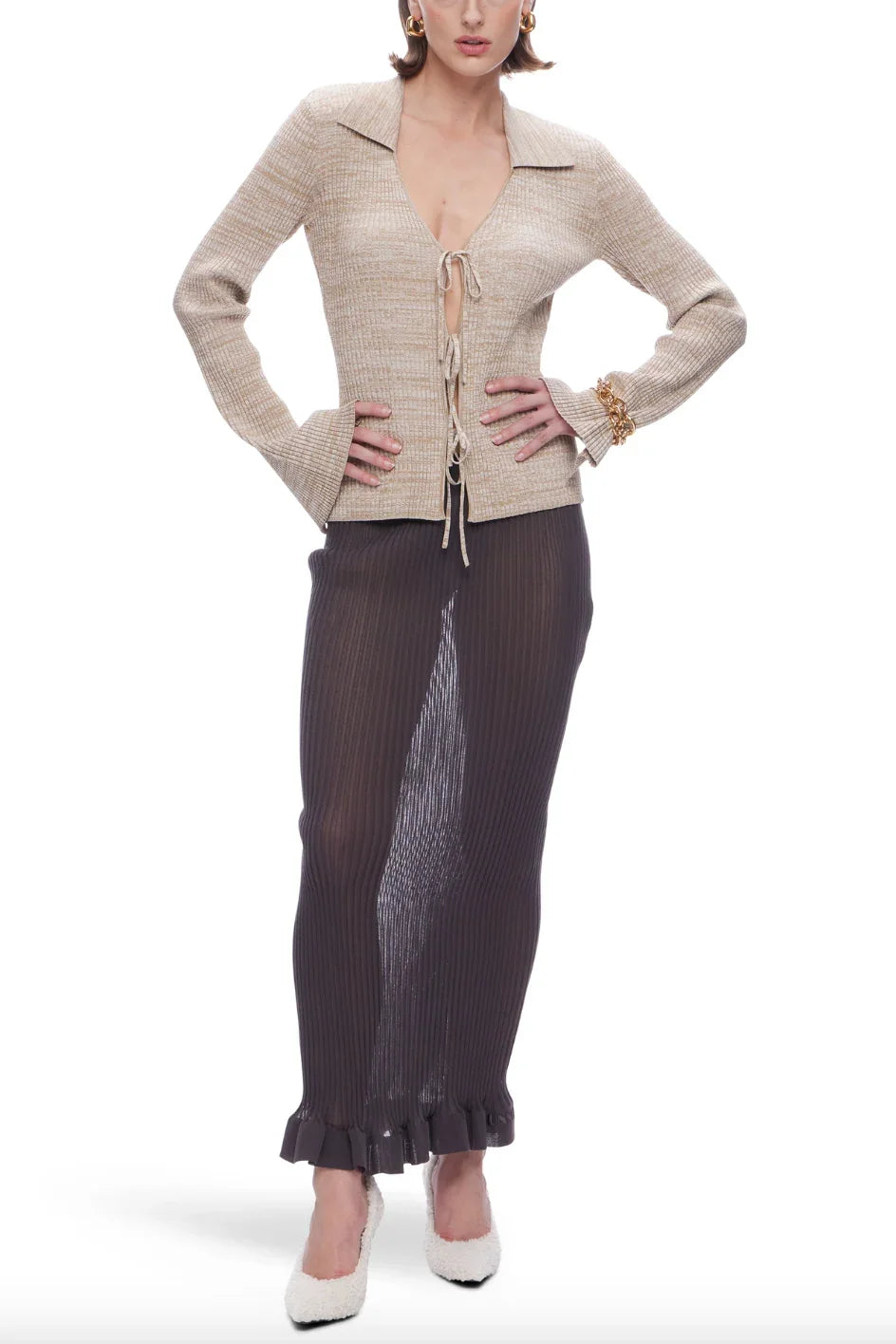 Woman wearing beige knit cardigan with ties and dark ribbed maxi skirt with ruffled hem