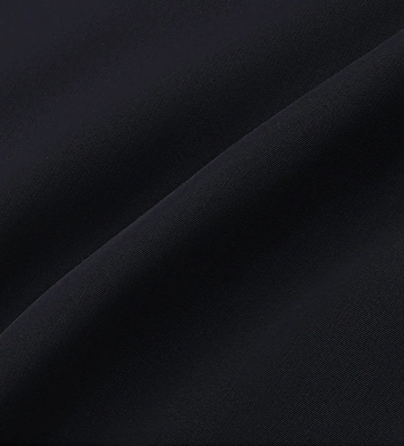 Close-up of smooth black fabric texture with diagonal folds and soft shadows