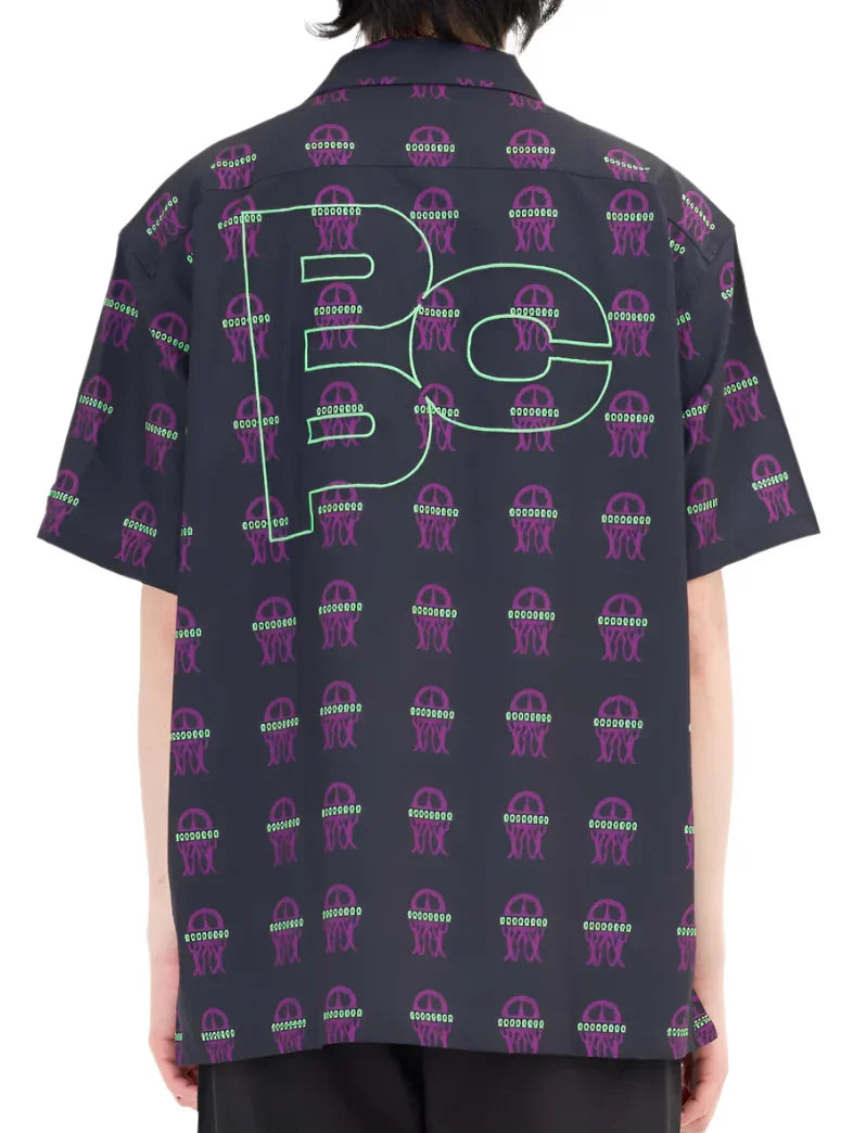 Back view of person wearing a black short-sleeve shirt with purple jellyfish pattern and large green outlined 'Be' text