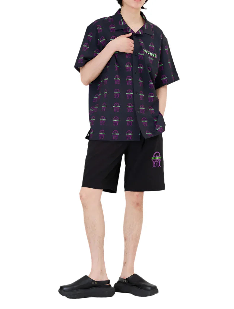 Man wearing black short-sleeve button-up shirt and shorts with colorful pattern and black slip-on shoes