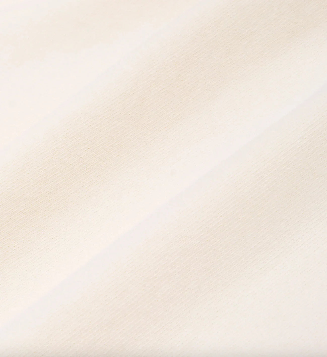 Close-up of soft cream-colored fabric texture with subtle diagonal folds
