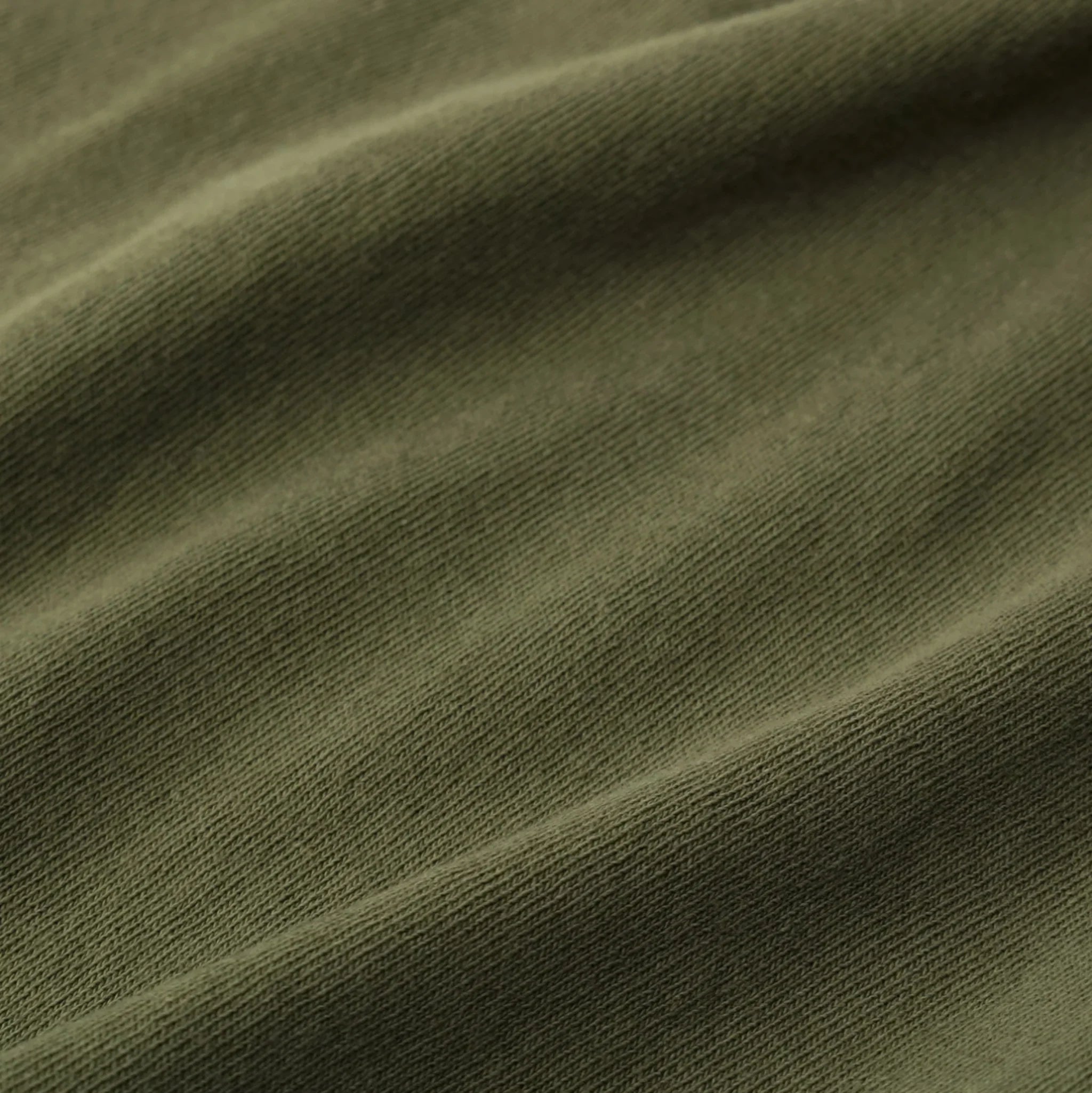 Close-up of olive green ribbed knit fabric with soft folds and texture