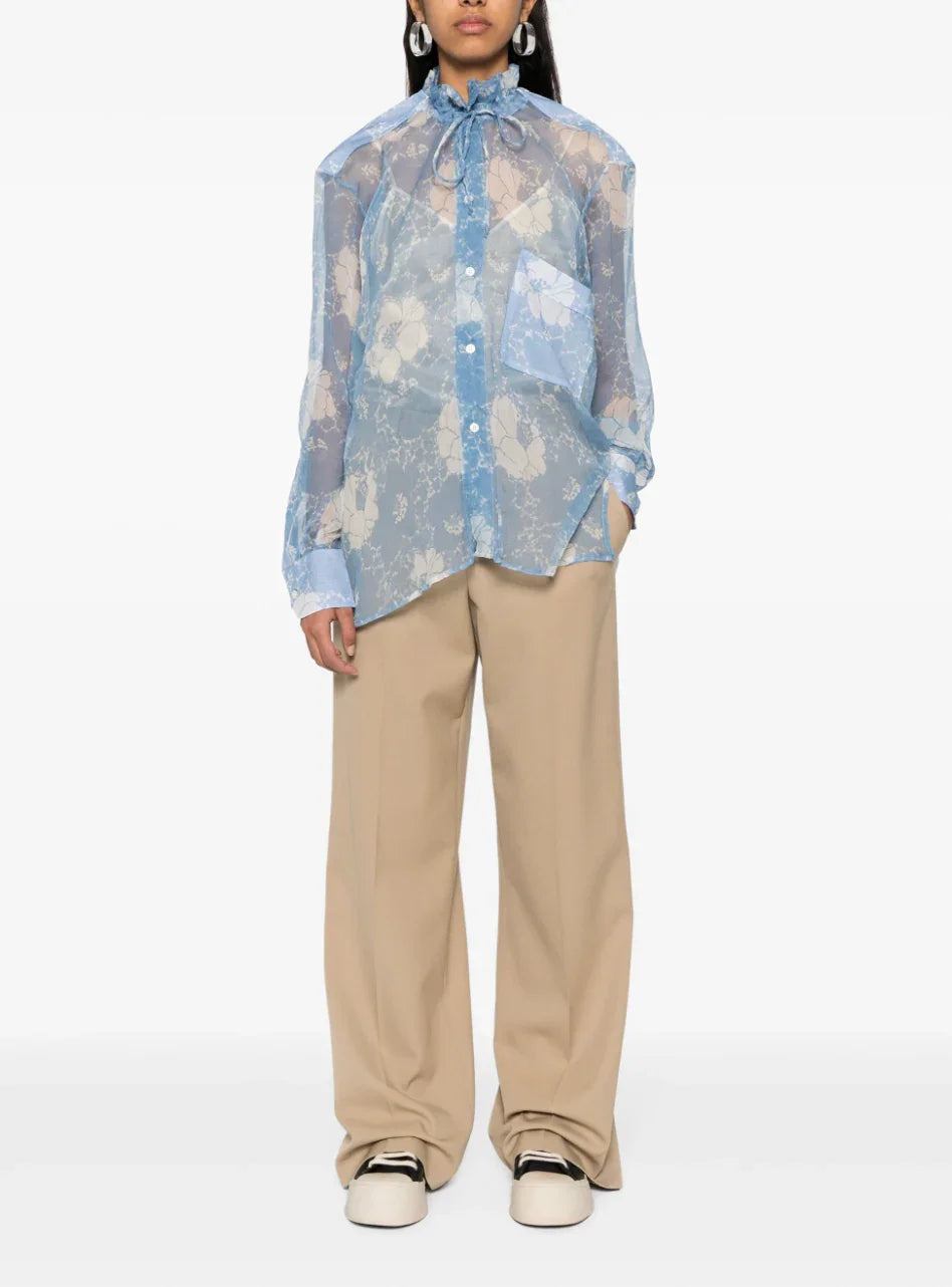 Fashion model wearing sheer blue floral lace blouse with bow neck and beige wide-leg pants