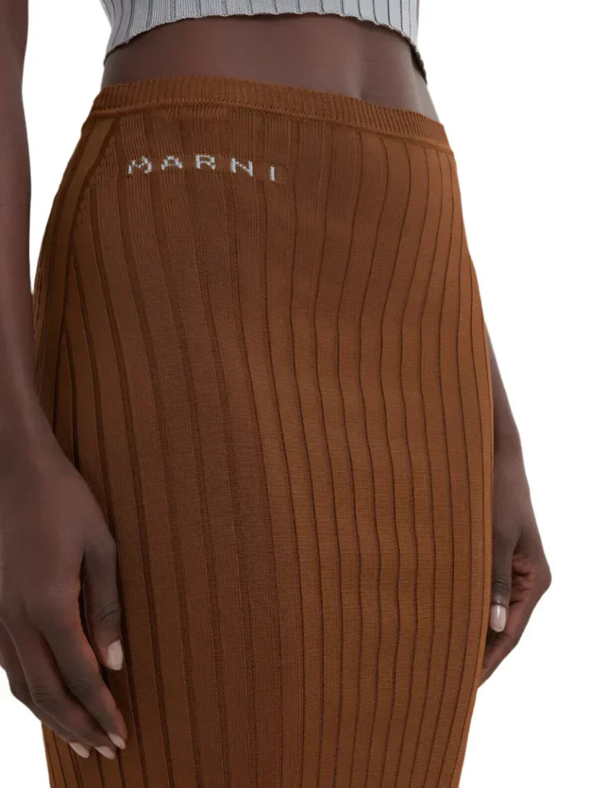 Close-up of brown ribbed knit skirt with Marni logo detail on waist, worn with white crop top
