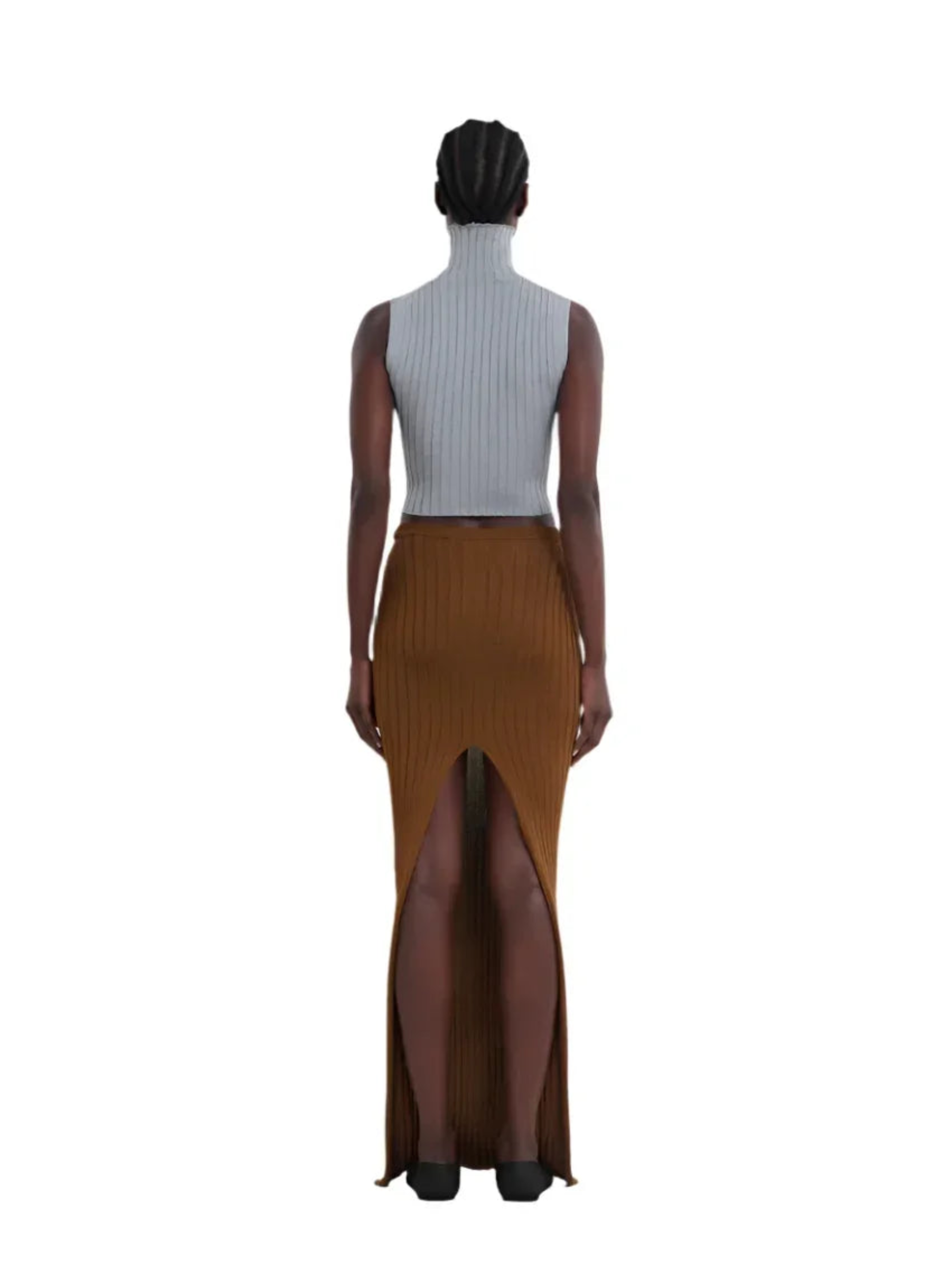 Back view of woman wearing sleeveless gray turtleneck top and long brown ribbed skirt with high slit