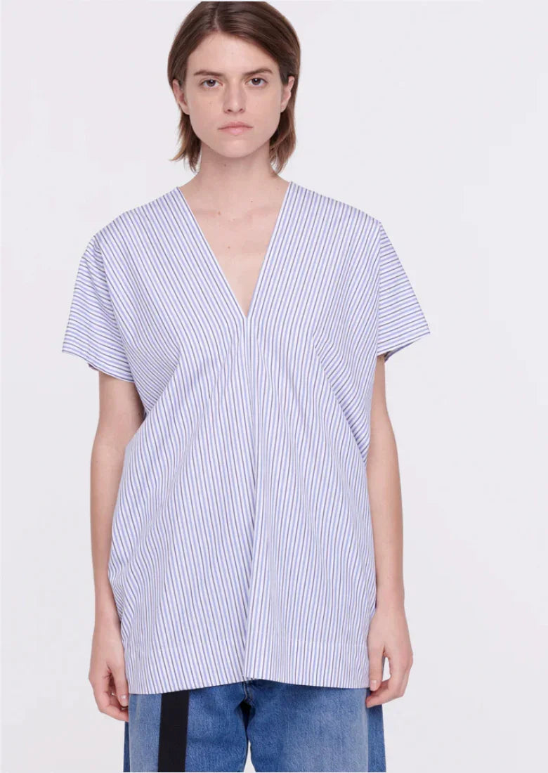 Young woman wearing blue and white vertical striped V-neck short sleeve top with blue jeans