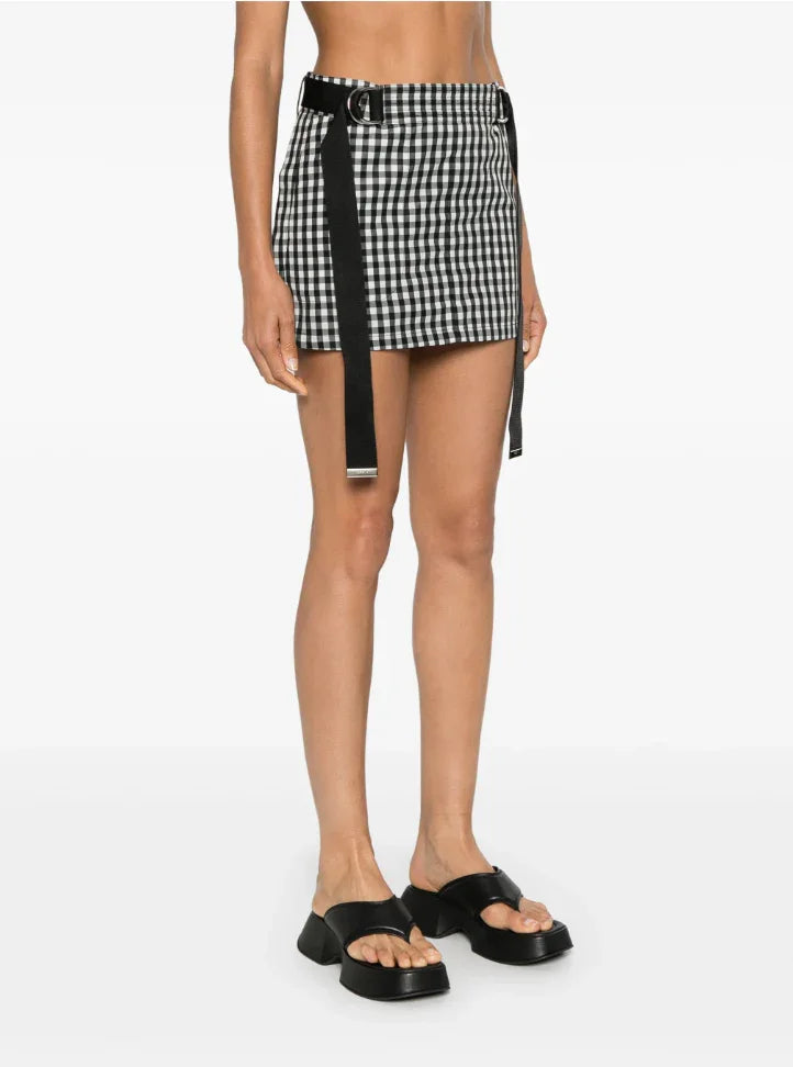 Woman wearing black and white checkered mini skirt with black belt and black platform sandals