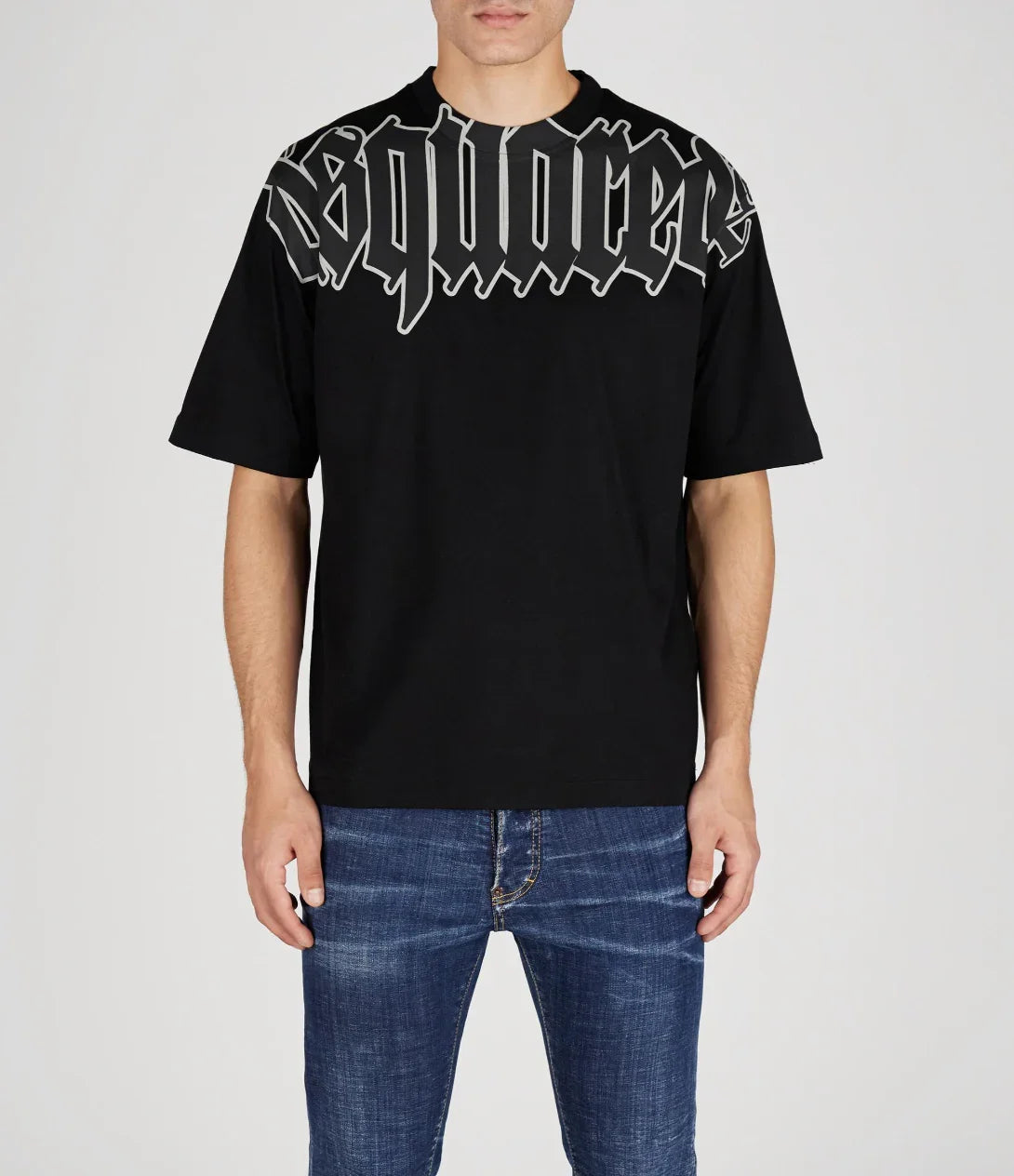 Man wearing black Dsquared2 t-shirt with bold gothic logo across chest and blue jeans