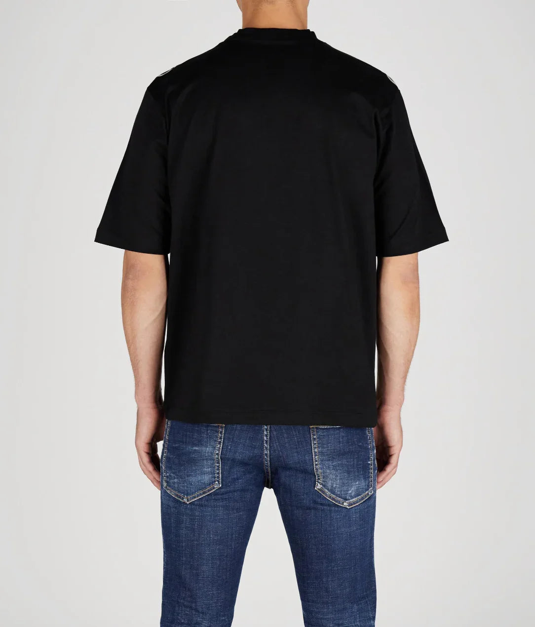 Man wearing plain black short-sleeve t-shirt and blue denim jeans, shown from the back