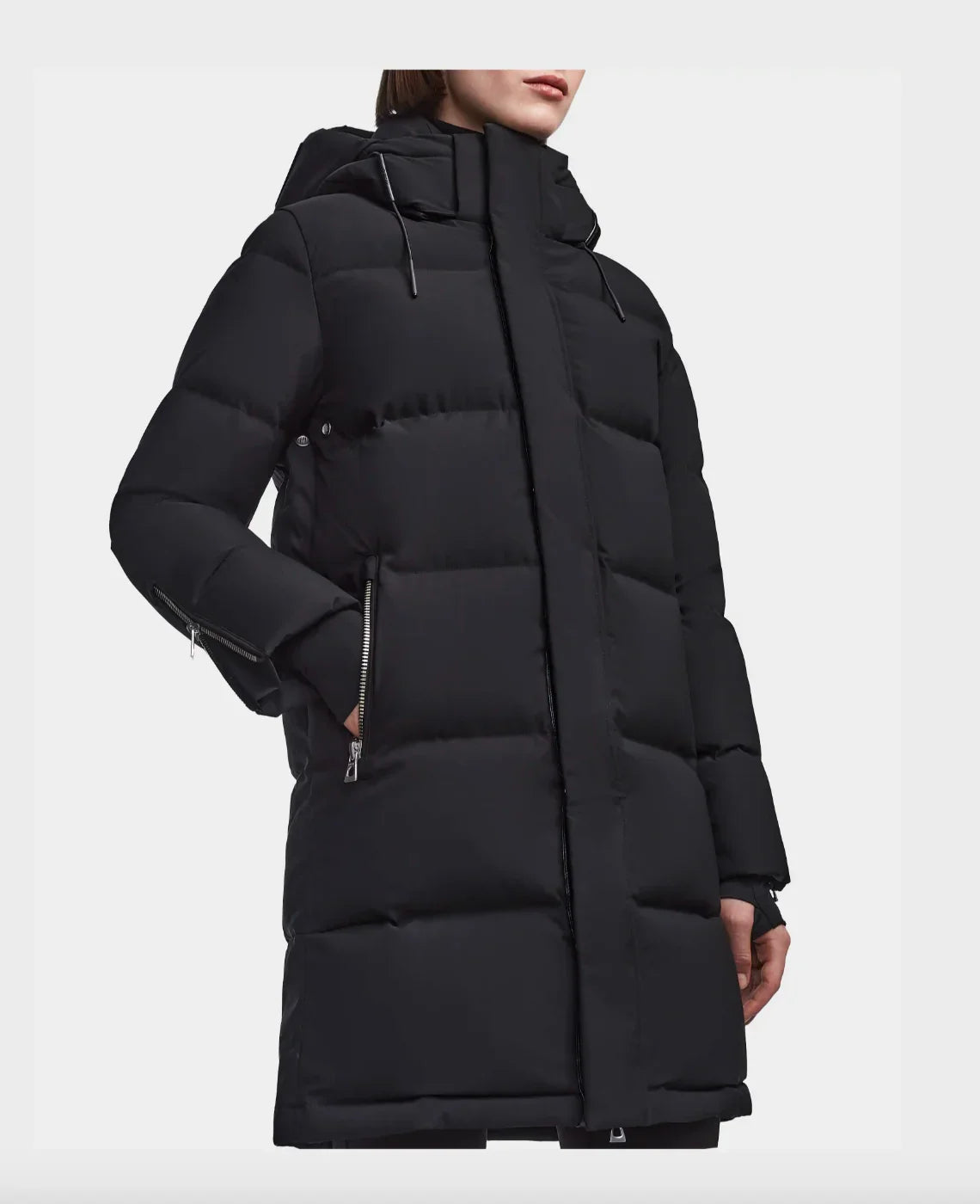 Black long puffer winter coat with hood and zipper pockets on female model