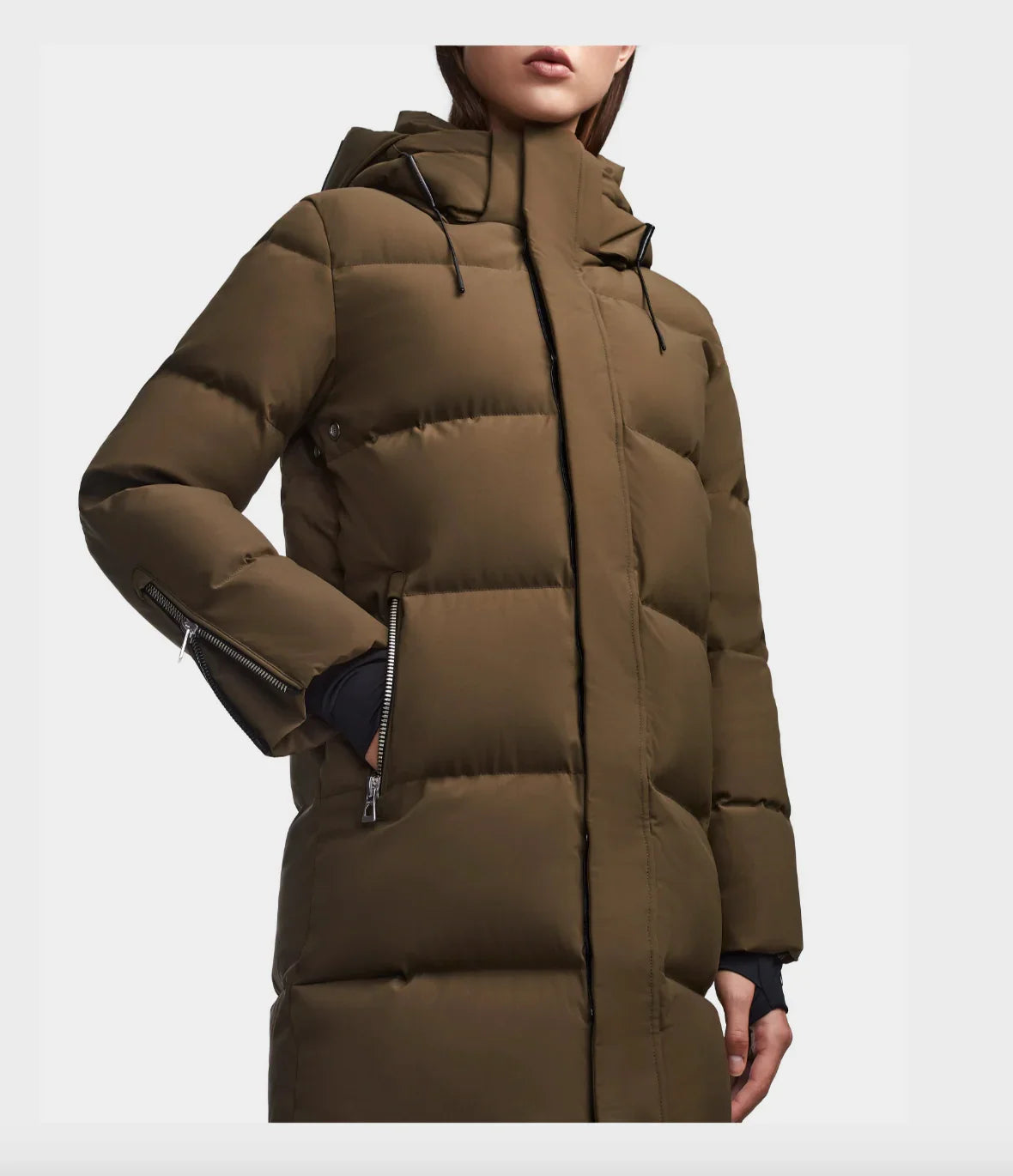 Close-up of woman wearing olive green padded winter coat with hood and zippered pockets
