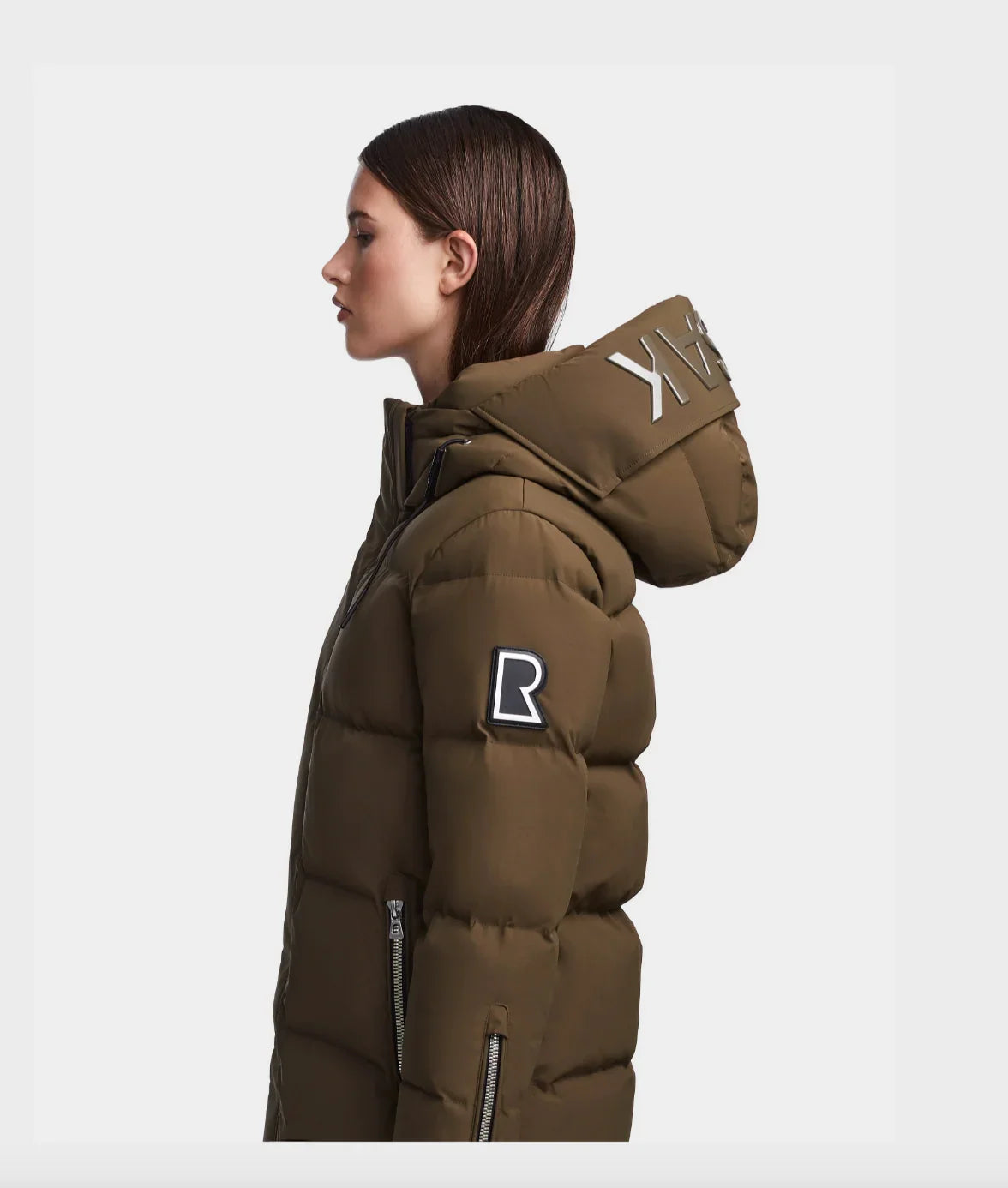 Profile of woman wearing brown puffer winter jacket with hood and logo patch on sleeve
