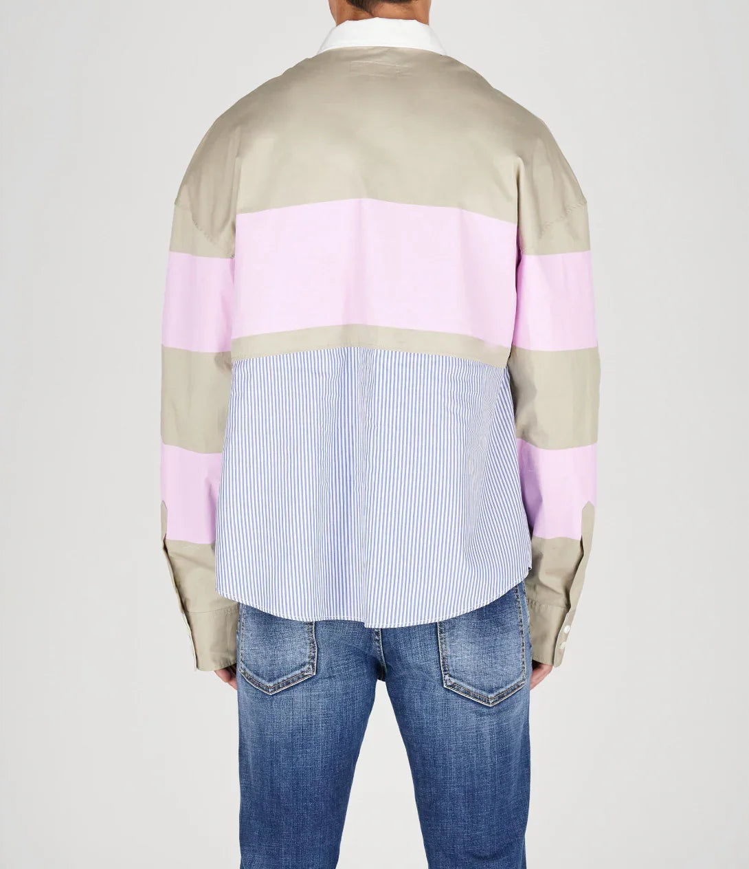 Back view of person wearing a color block shirt with beige, pink, and blue stripes paired with blue denim jeans