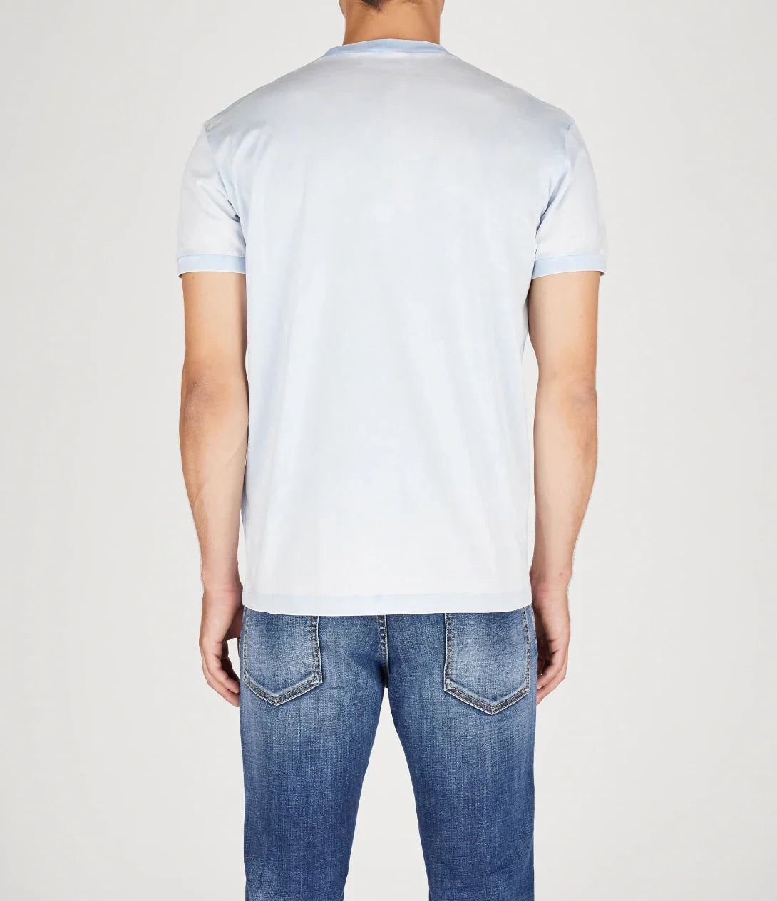 Rear view of man wearing light blue ringer t-shirt and blue denim jeans against white background