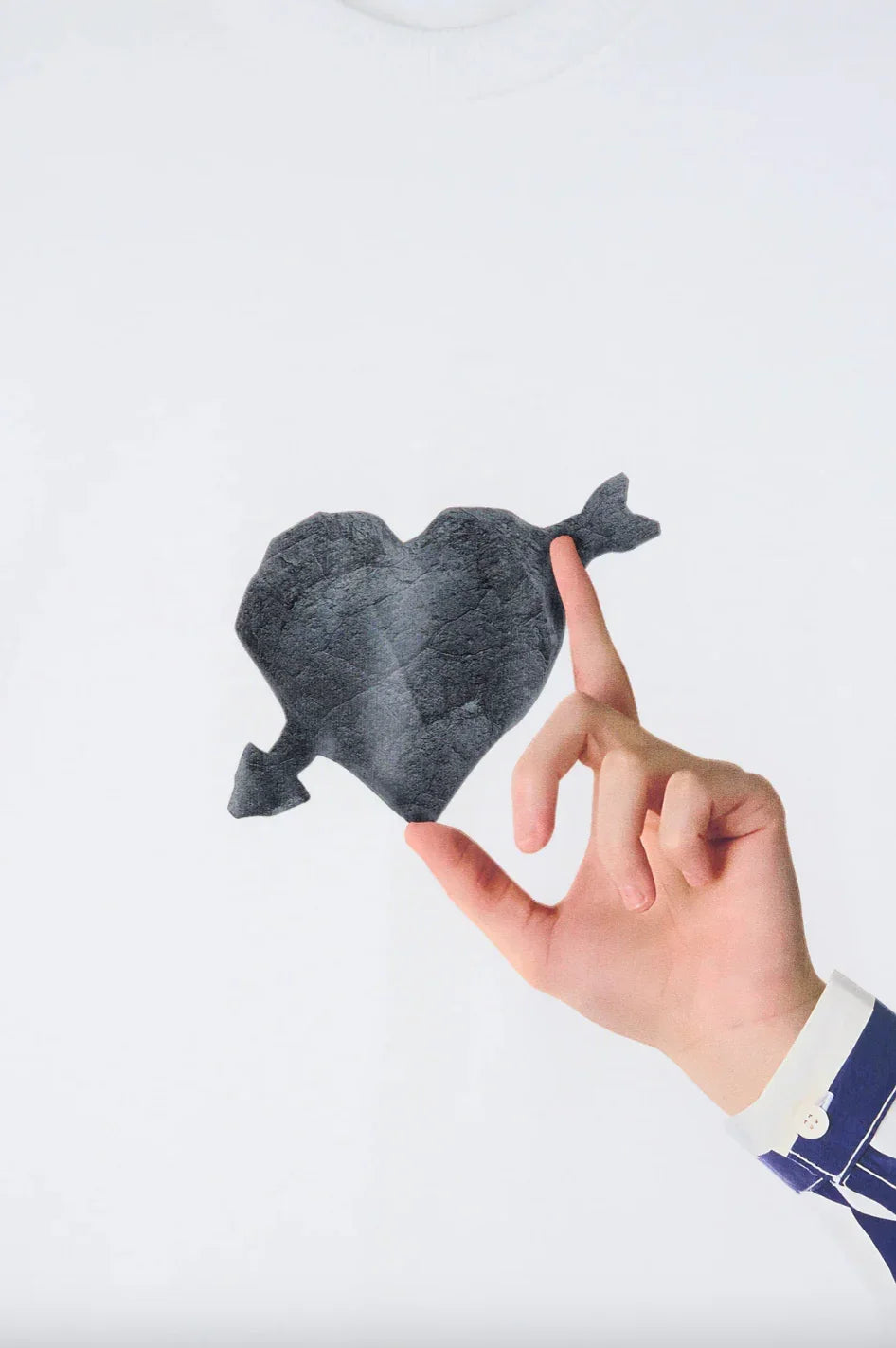 Hand holding a black cracked stone heart with an arrow through it on white background