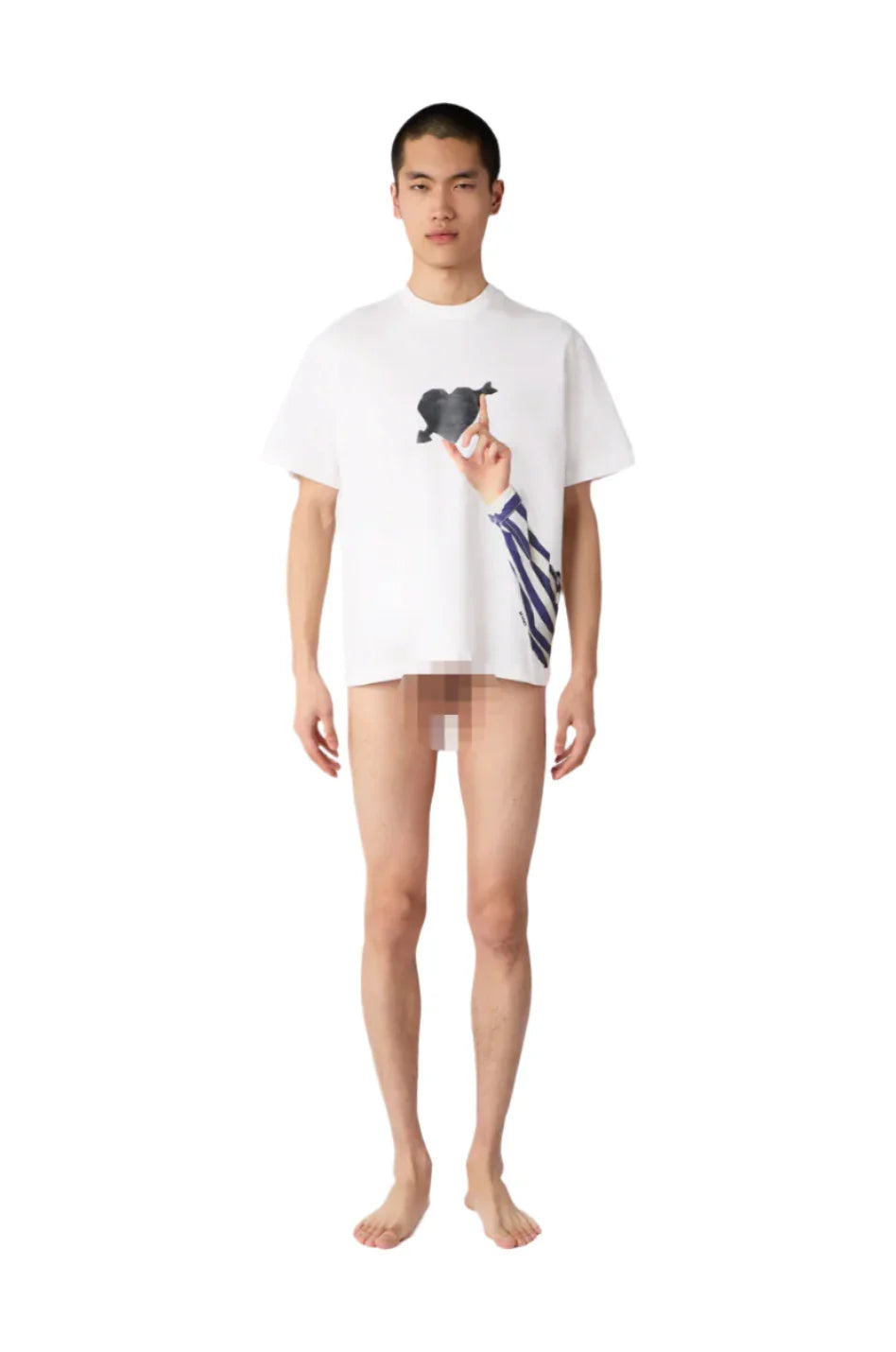 Male model wearing oversized white graphic t-shirt with hand and striped sleeve print, standing barefoot