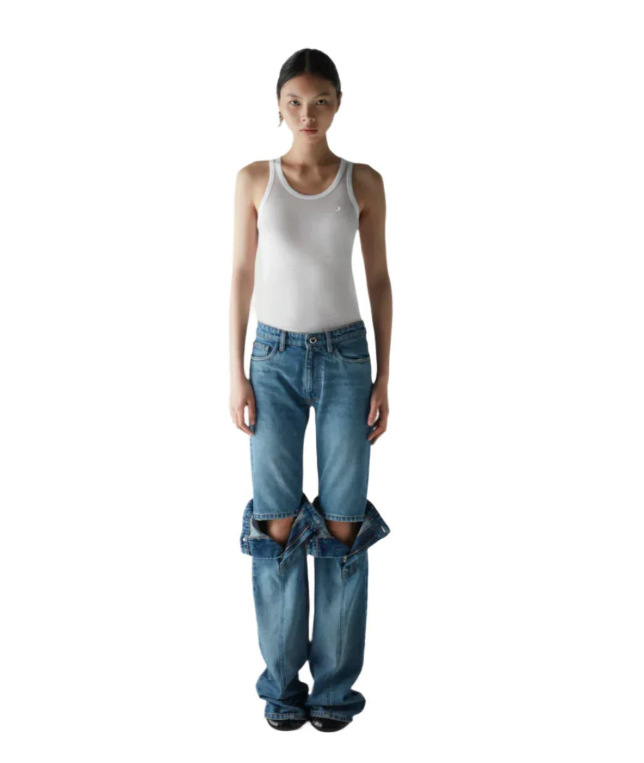 Woman wearing unique blue denim cutout jeans with white tank top on white background