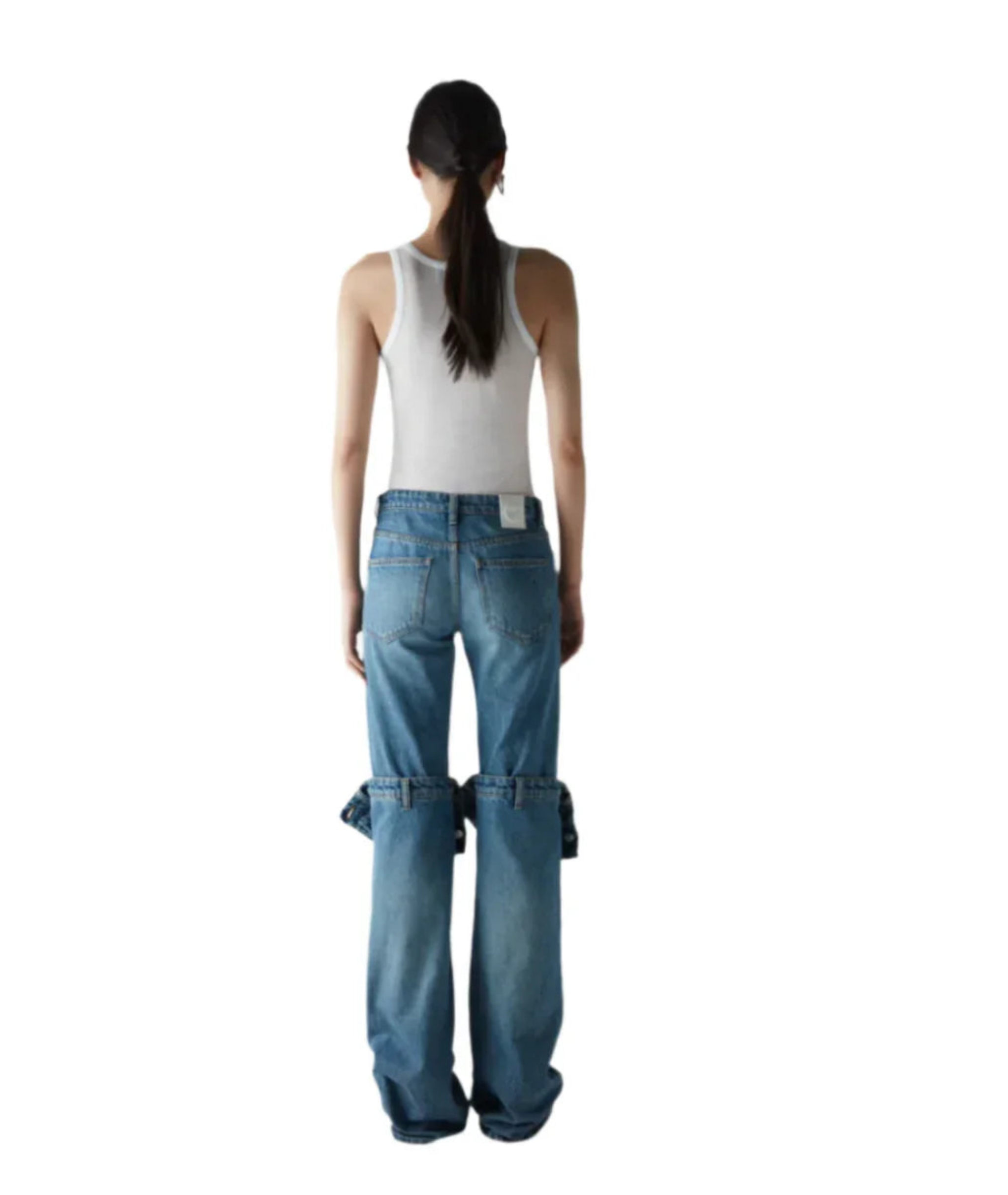 Woman wearing white sleeveless top and blue jeans with detachable lower legs shown from back
