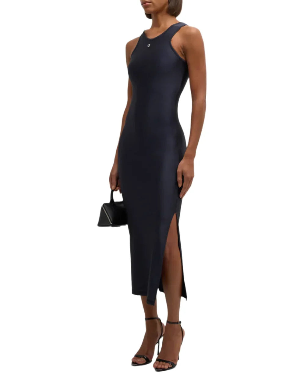 woman in a sleeveless black midi dress with side slit, black heels, and small black handbag