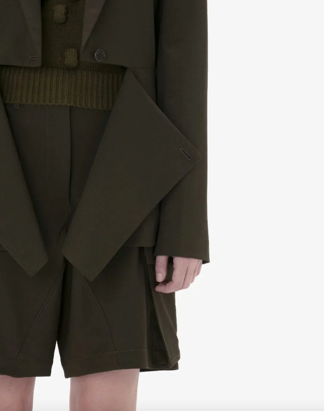 Close-up of a person wearing dark olive green tailored blazer over matching shorts with knit waistband