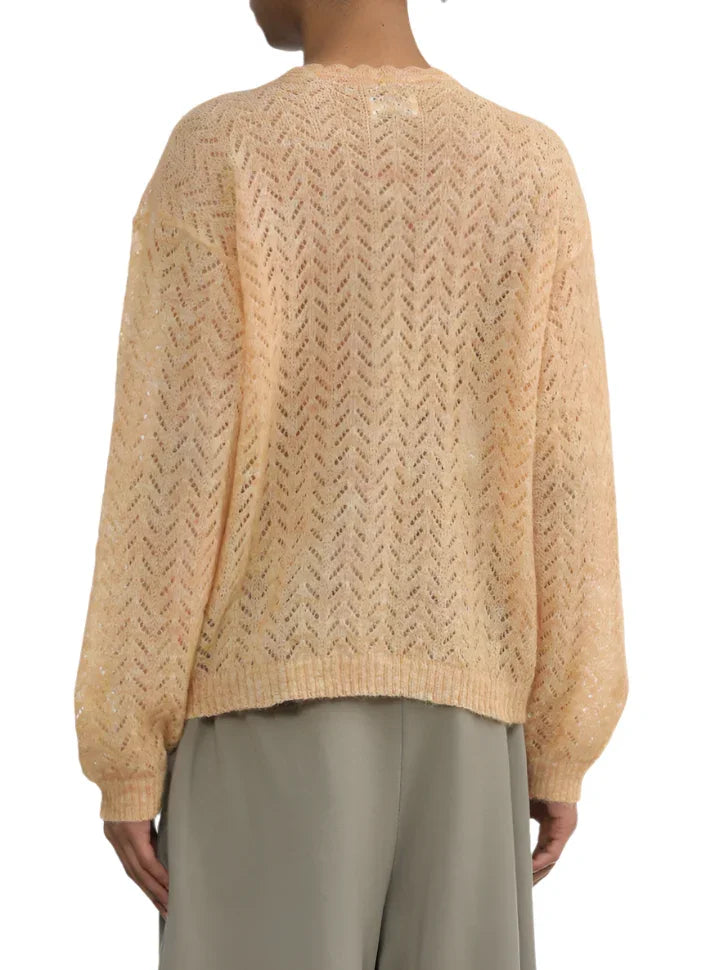 Back view of person wearing peach knit sweater with chevron pattern and loose gray pants
