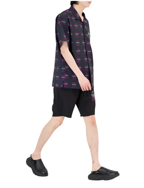 Man wearing black short-sleeve button-up shirt with purple and green jellyfish print and matching black shorts with jellyfish design