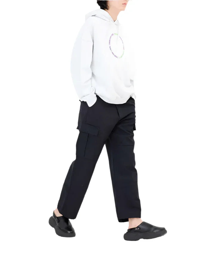 Person wearing white hoodie and black cargo pants walking in black slip-on shoes