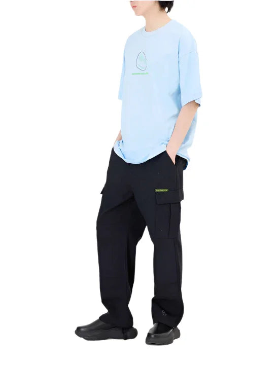Side view of a person wearing a light blue graphic t-shirt and black cargo pants with chunky black shoes