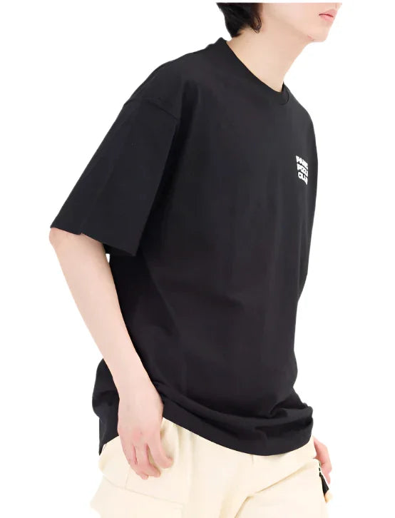Side view of person wearing black graphic tee and beige shorts on white background