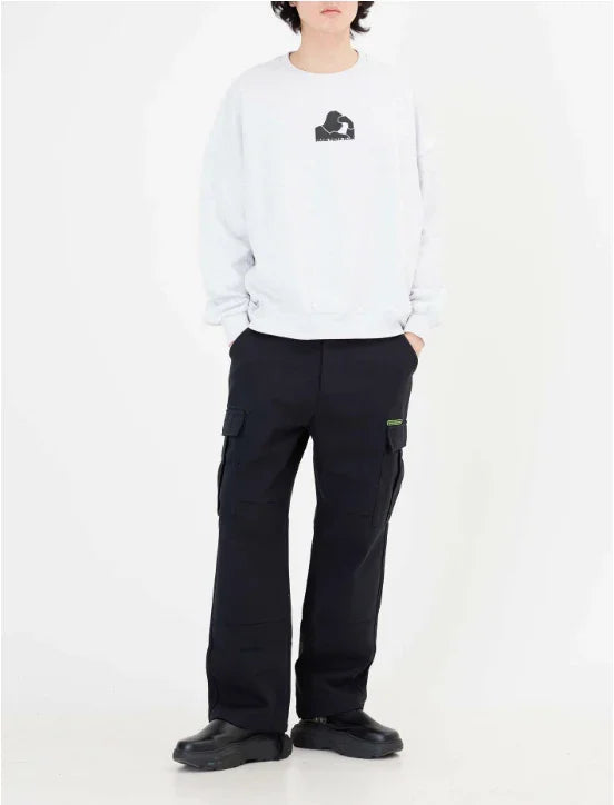 Model wearing white sweatshirt with graphic and black cargo pants with pockets and black shoes on white background