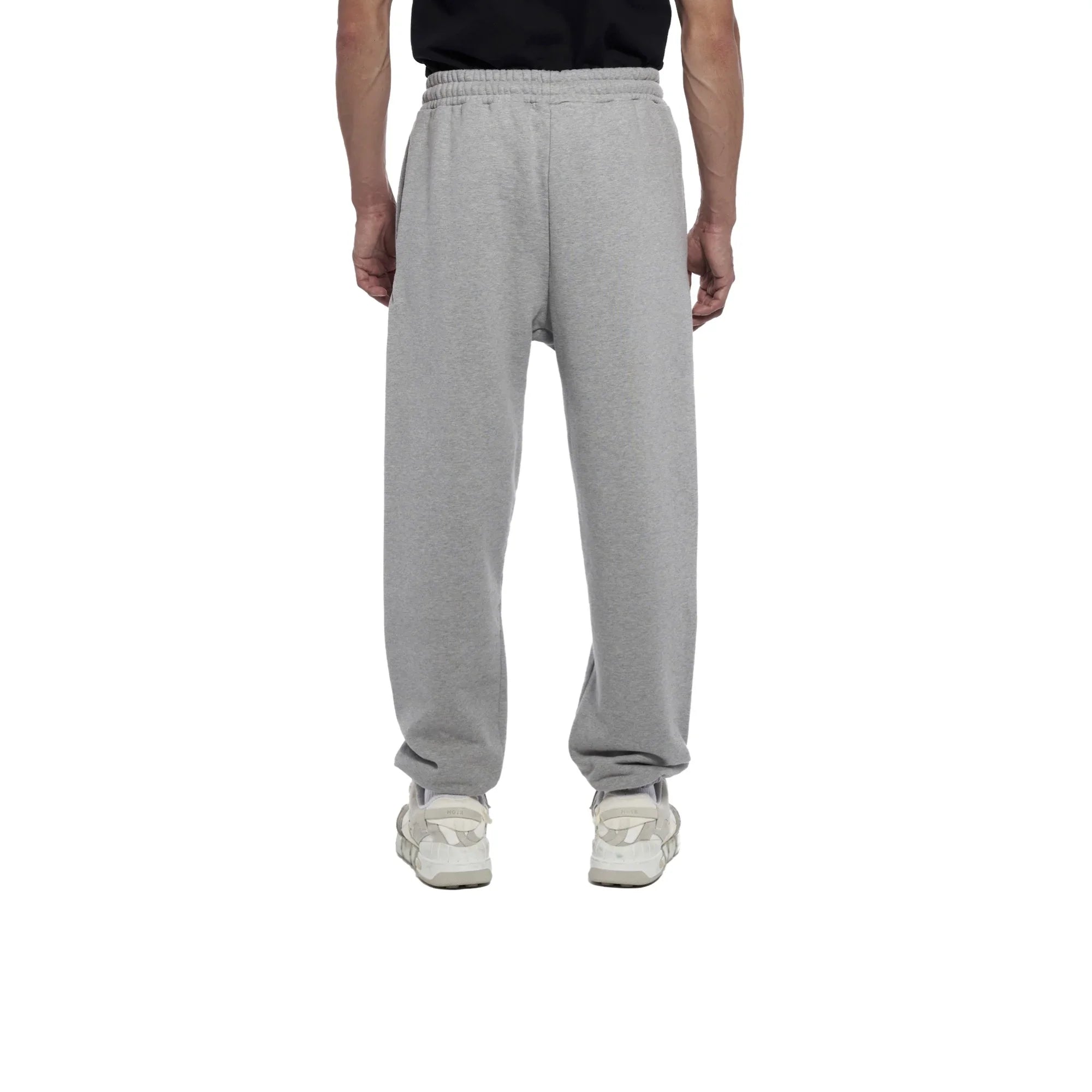 Rear view of person wearing grey sweatpants and white sneakers on white background