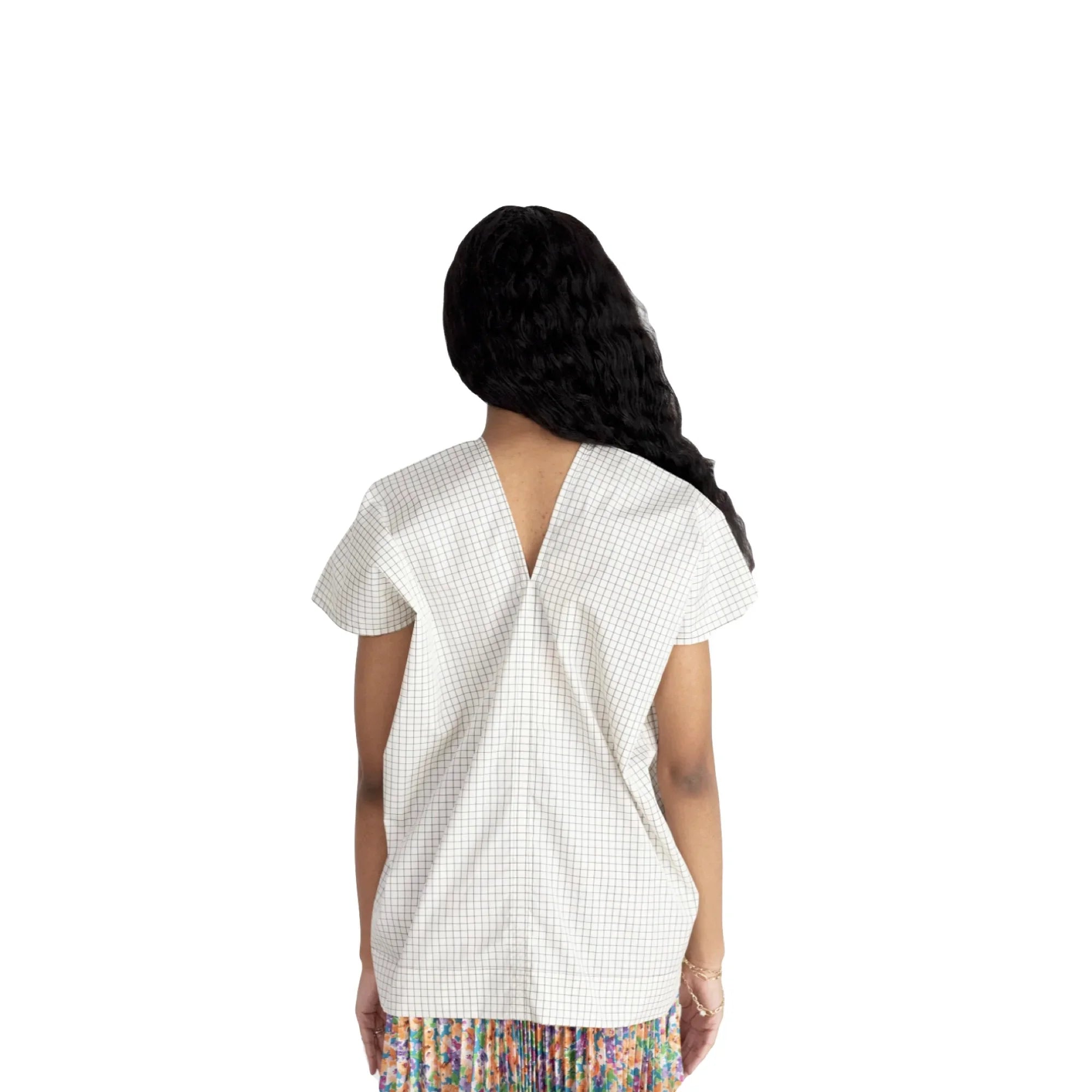 Woman wearing white checkered blouse with V-back and short sleeves, paired with a colorful floral skirt