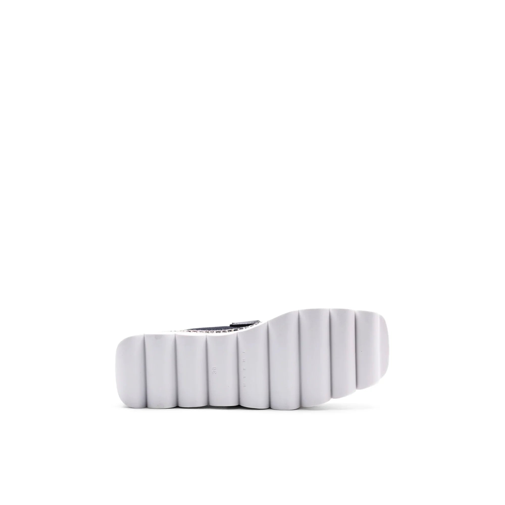 White segmented sole of a black and white patterned sneaker on white background