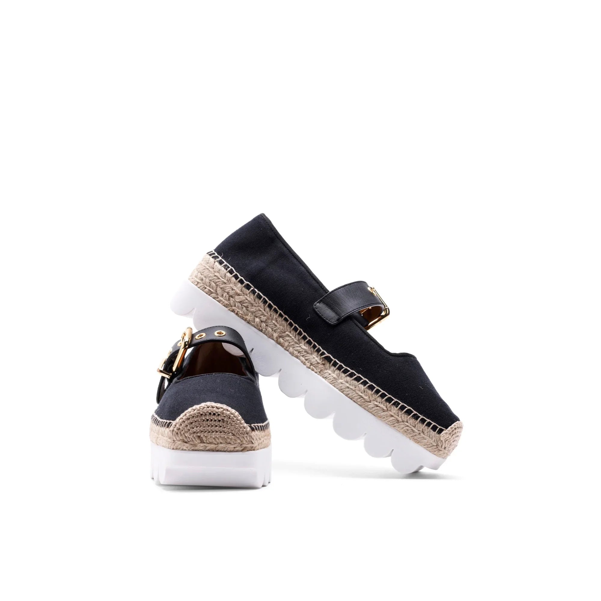 Black espadrille shoes with woven jute trim, white chunky soles, and gold buckle strap