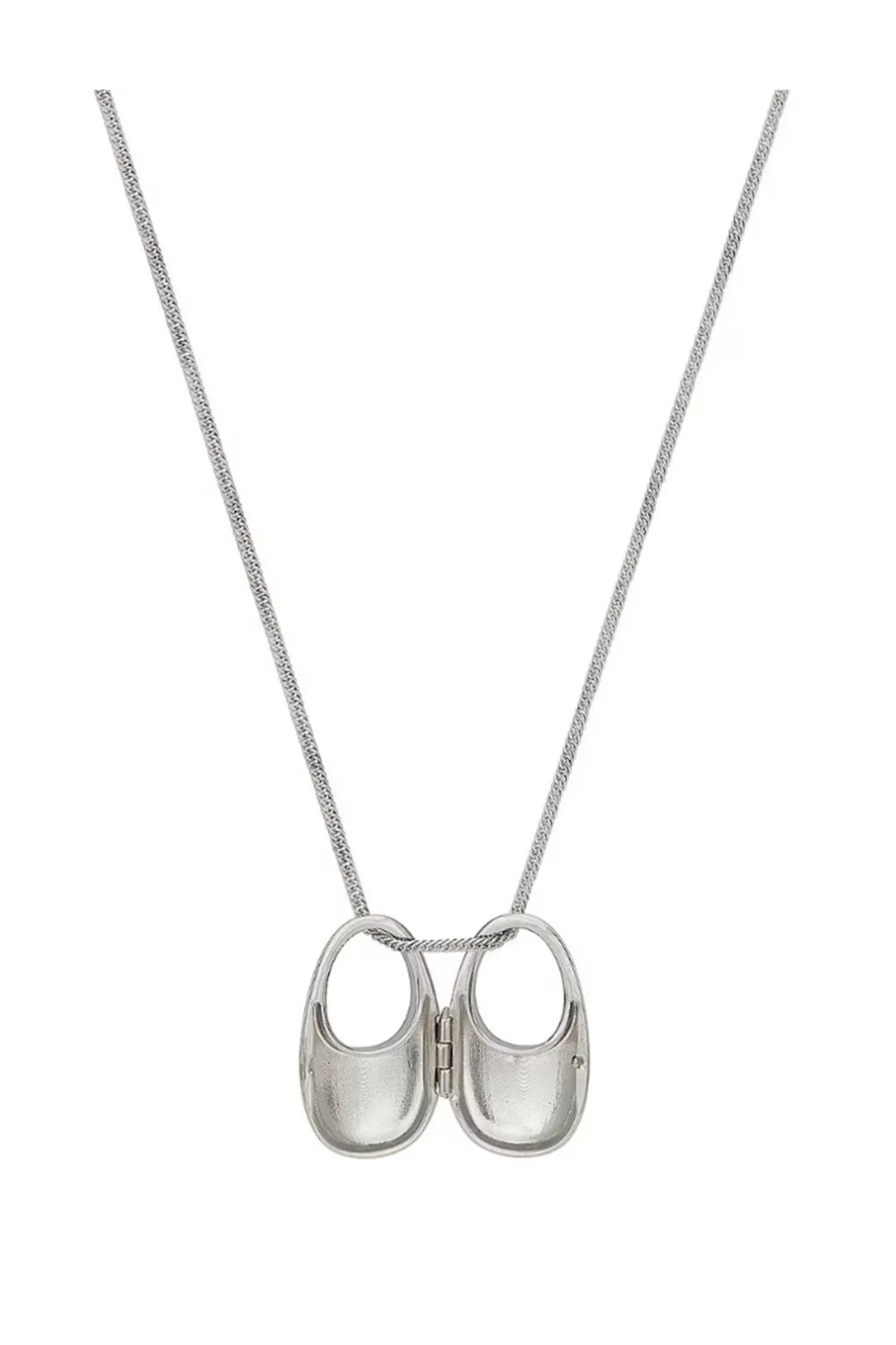 Silver necklace with two small hinged baby shoe pendants on a chain on white background