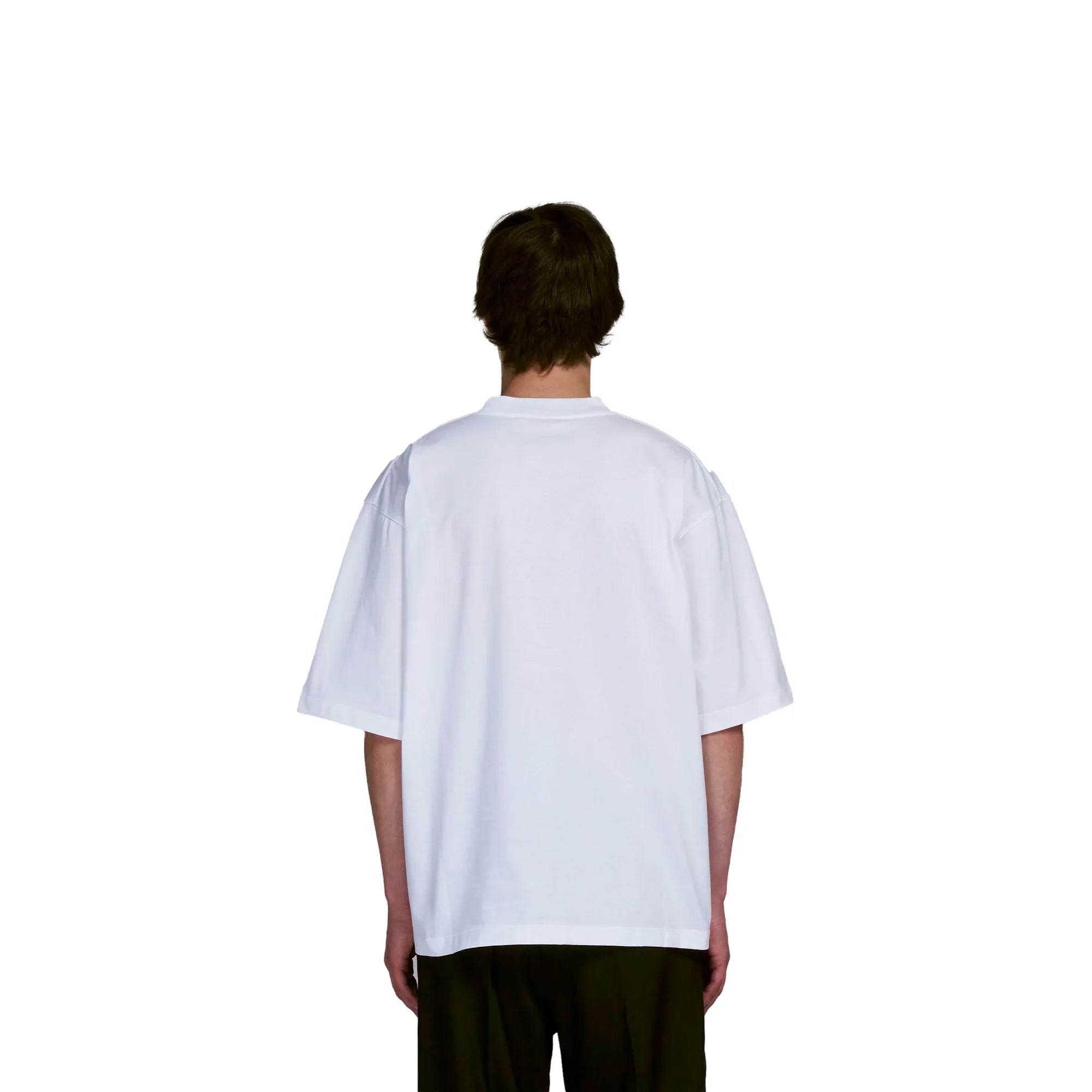 Back view of a person wearing a plain oversized white t-shirt and black pants on plain white background