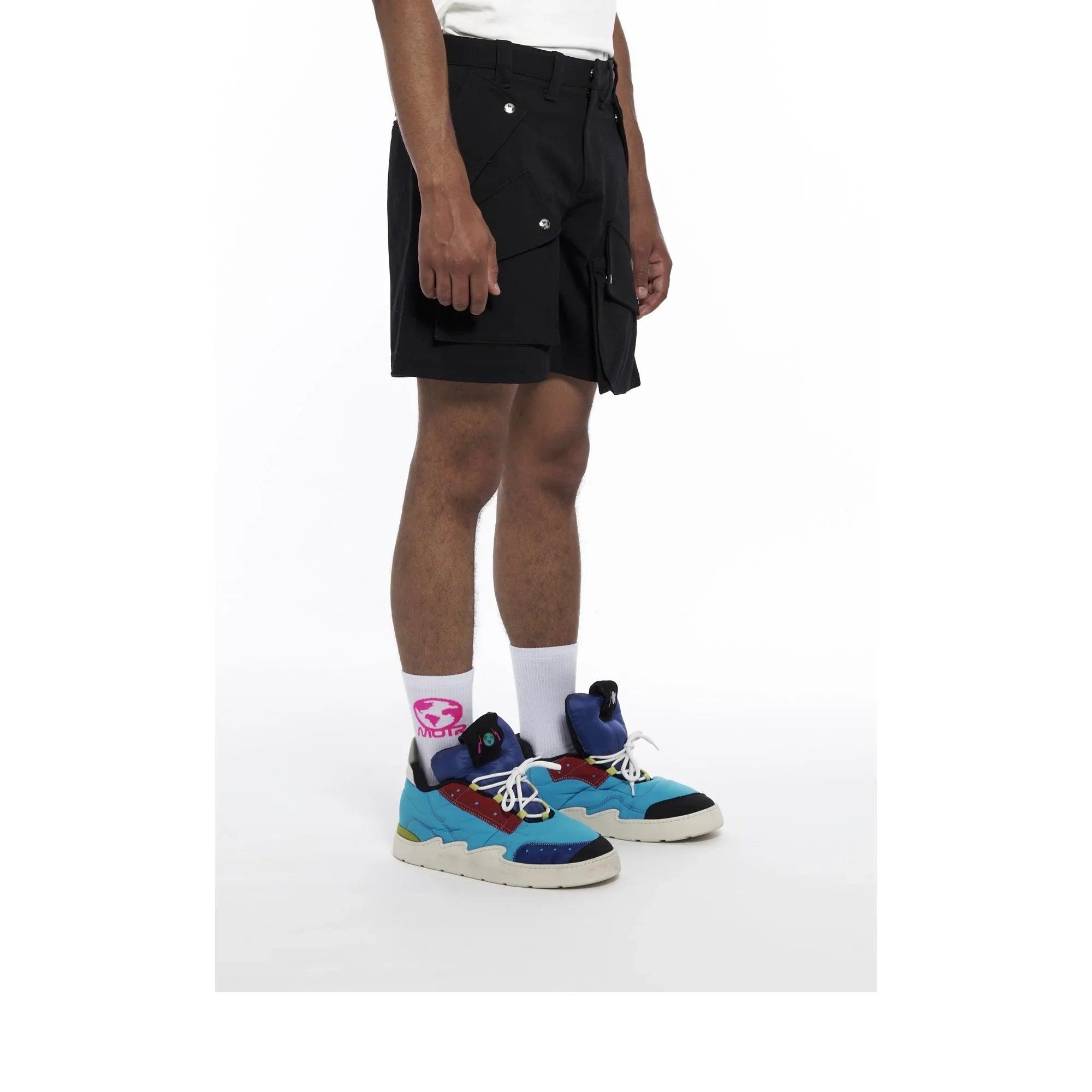 Person wearing black cargo shorts with large pockets and colorful blue sneakers with white socks