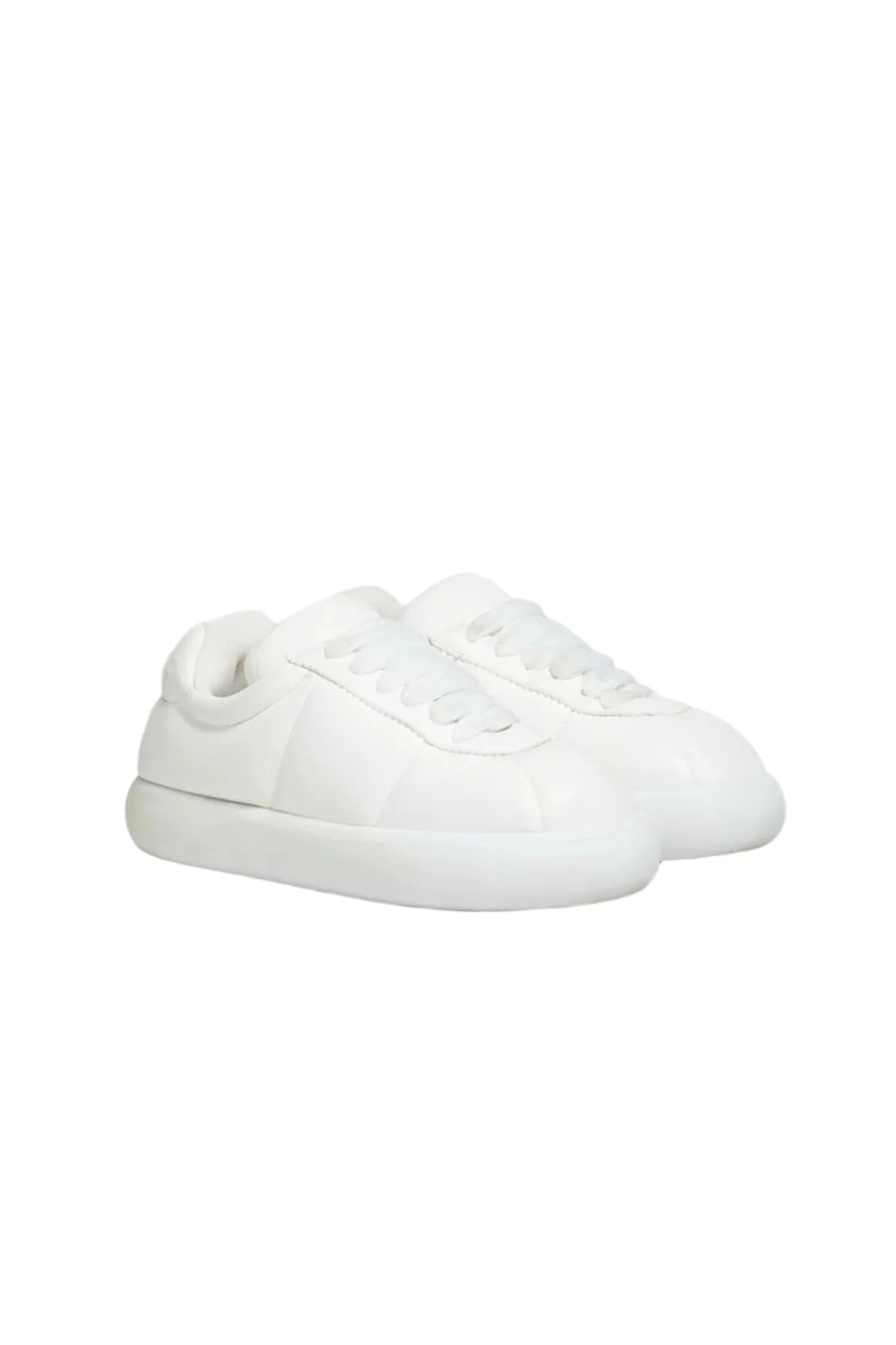 Minimalist white sneakers with thick sole and stitched detailing on a white background
