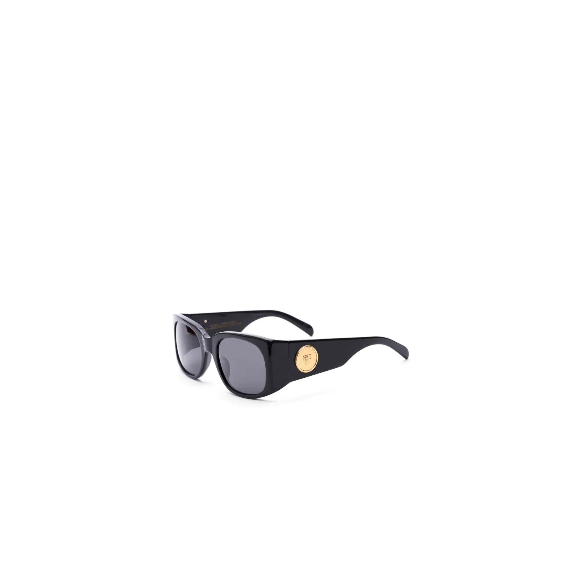 Stylish black sunglasses with dark lenses and gold circular emblem on the temple, isolated on white