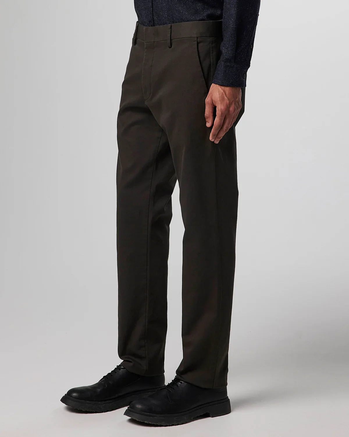 Man wearing dark brown slim-fit trousers with black leather shoes and a dark shirt