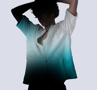 Woman wearing a gradient blue and white blouse against a light gray background