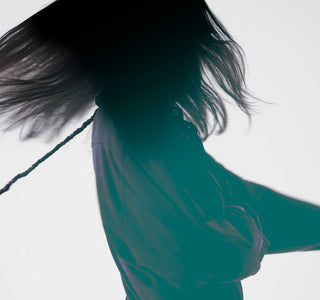 Person with long hair and a green shirt against a white background